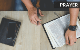 Anonymous man sitting at a table with an open Bible, getting ready to pray.